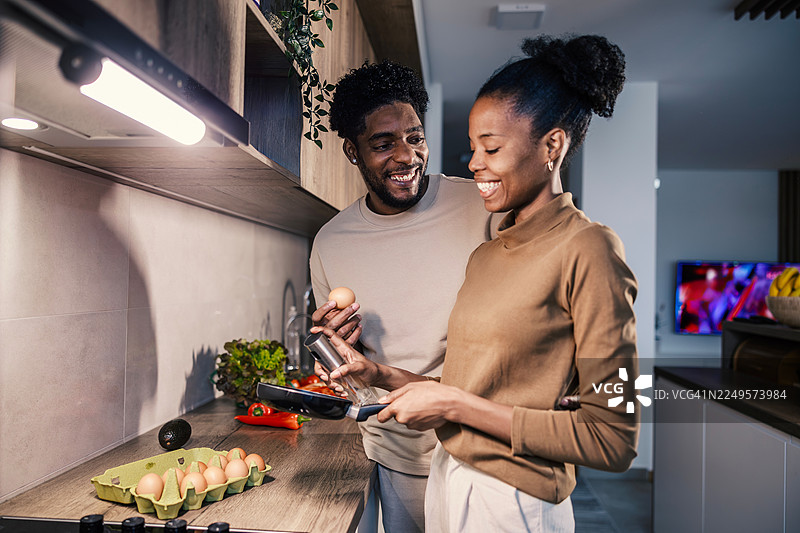 快乐的黑人夫妇在厨房里做早餐图片素材