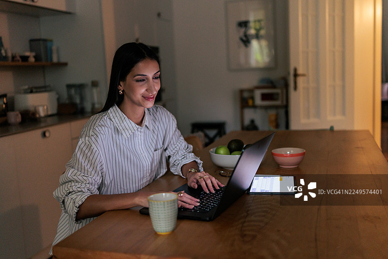 女子晚上在家使用笔记本电脑工作图片素材