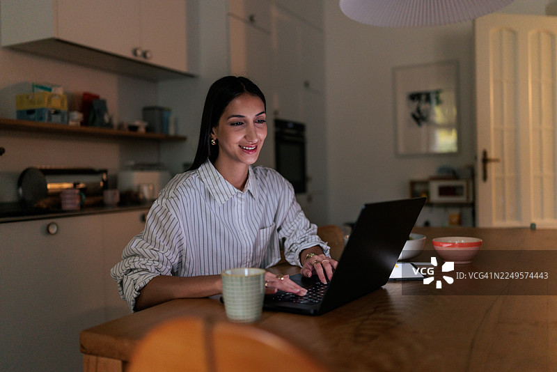 女子晚上在家使用笔记本电脑工作图片素材