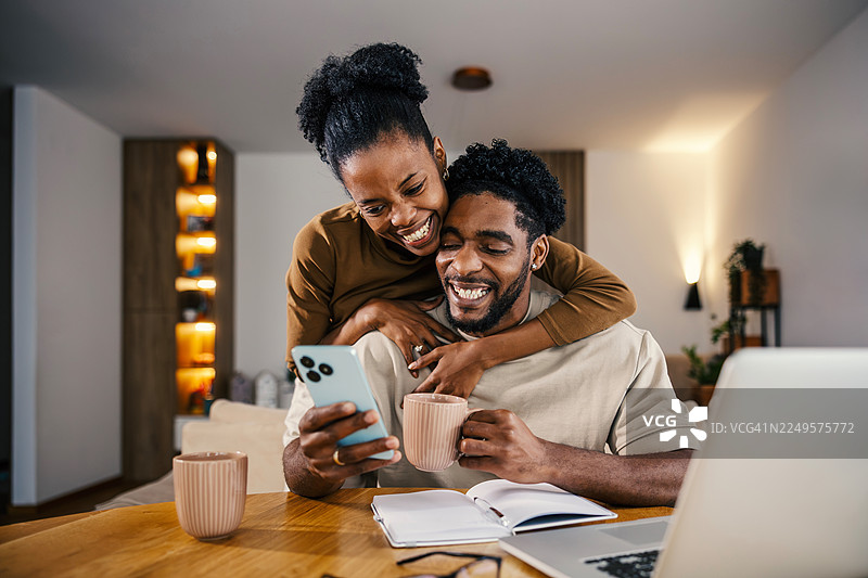 快乐的黑人夫妇在家中分享手机图片素材