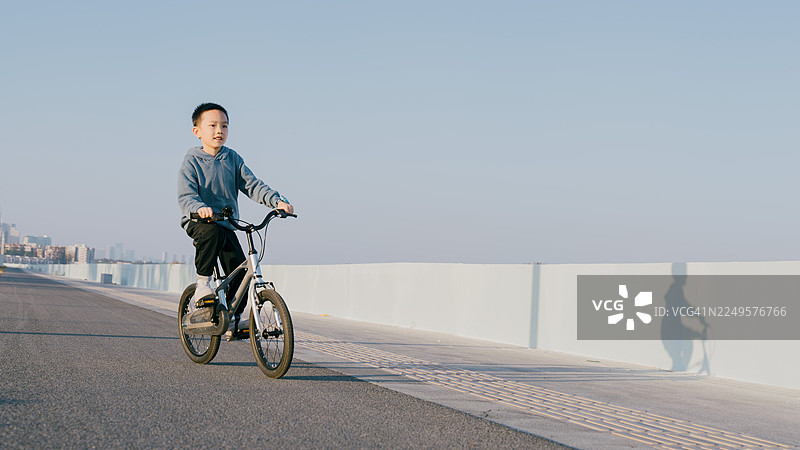 一个亚洲男孩在沙滩上骑自行车；亚洲家庭生活方式图片素材