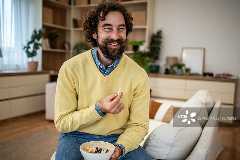 男人在家享用健康的早餐麦片，面带微笑图片素材