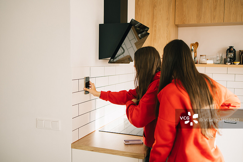 年轻女孩们在厨房里用吸盘手机壳录制视频图片素材