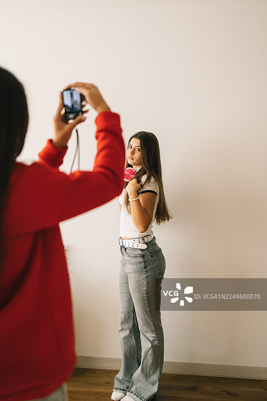 一位穿着休闲装的漂亮女孩在家对着老式相机摆拍图片素材