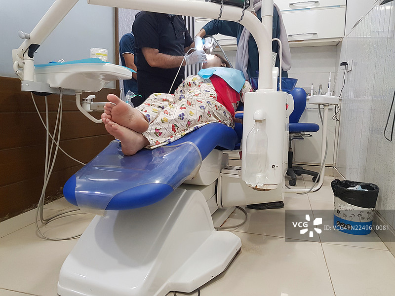 牙医和他的女助理在牙科诊所为一位成熟的成年女性前牙进行牙齿洁牙和抛光。图片素材