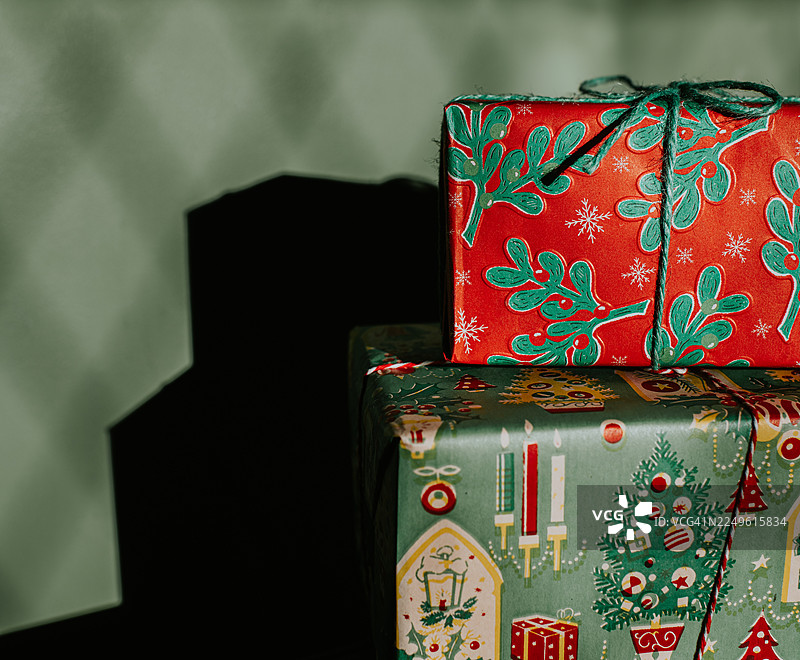 两个包装好的圣诞礼物堆叠在一个绿色的墙壁前图片素材