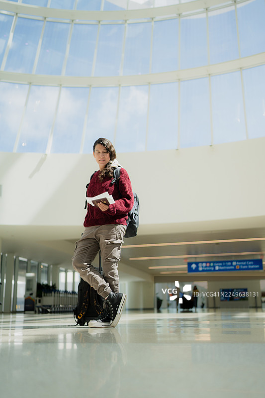 一位女士在机场航站楼内，手持护照，正在旅行图片素材