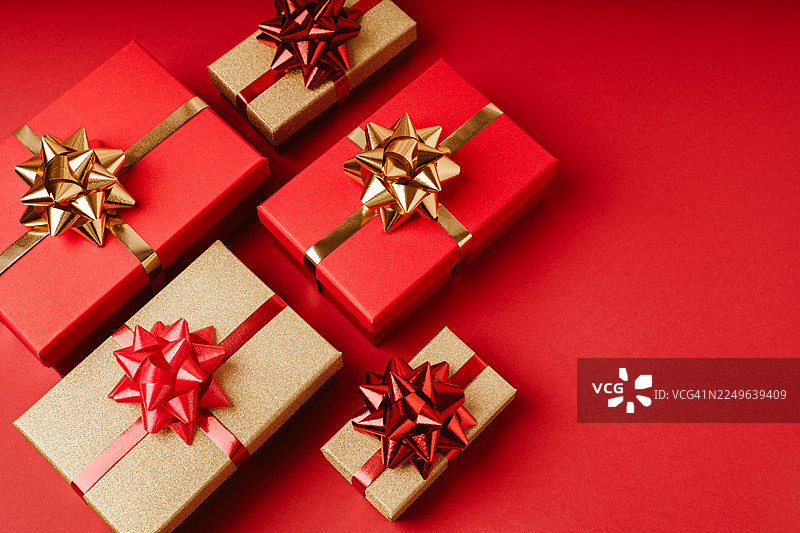 喜庆的红金色礼品盒，系着蝴蝶结，背景为鲜艳的红色图片素材