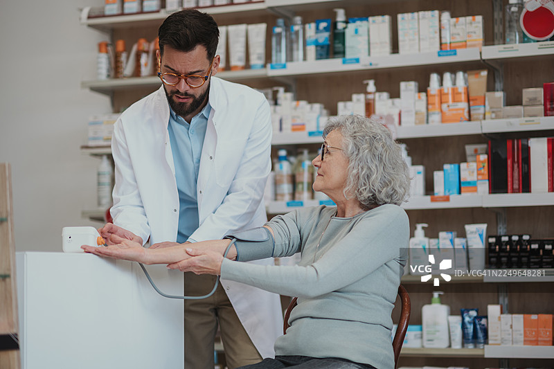 药剂师在药房为老年女性测量血压图片素材
