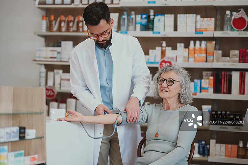 药剂师在药房为老年女性测量血压图片素材