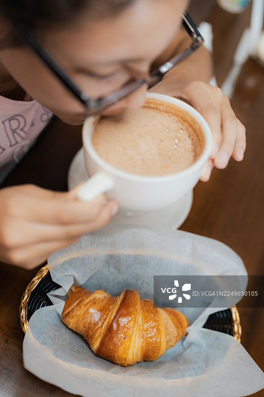 女人早餐喝咖啡配羊角面包图片素材
