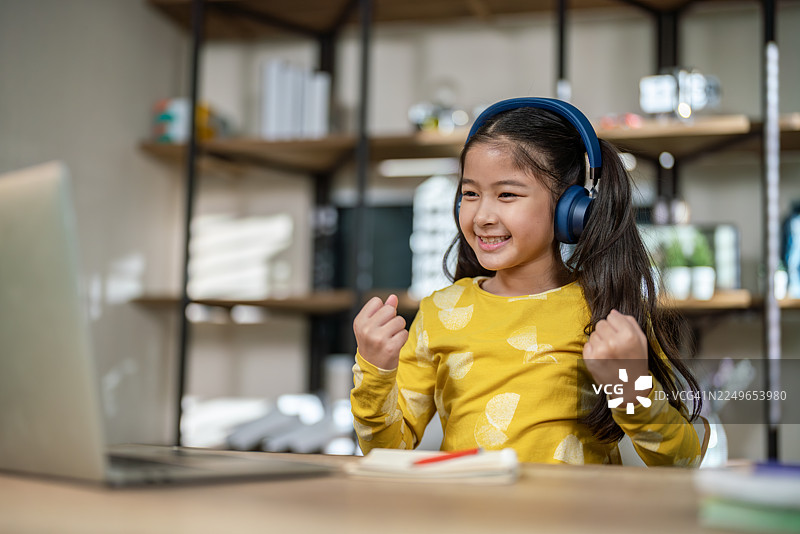 快乐的小学生戴着耳机用笔记本电脑学习图片素材