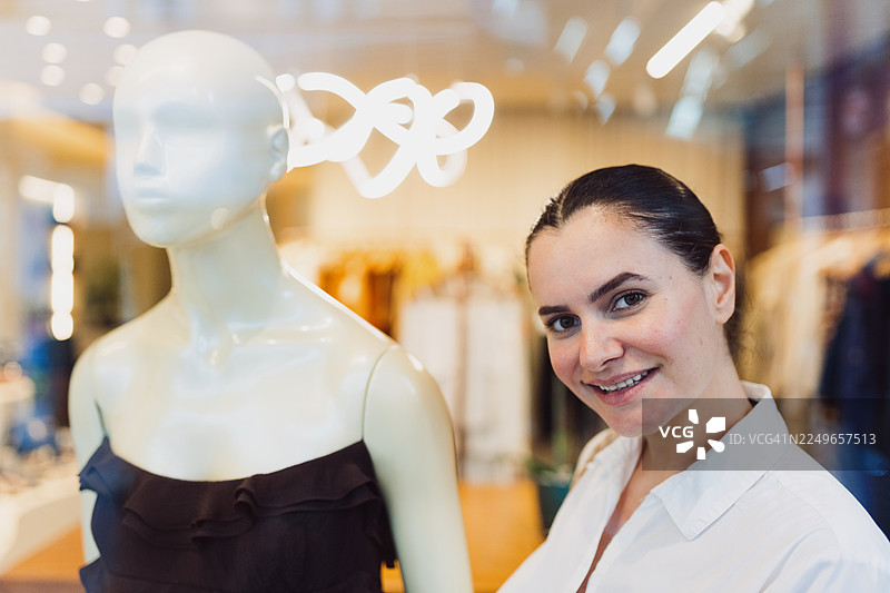 生活方式零售瞬间：女子在时尚精品店模特展示旁摆姿势图片素材