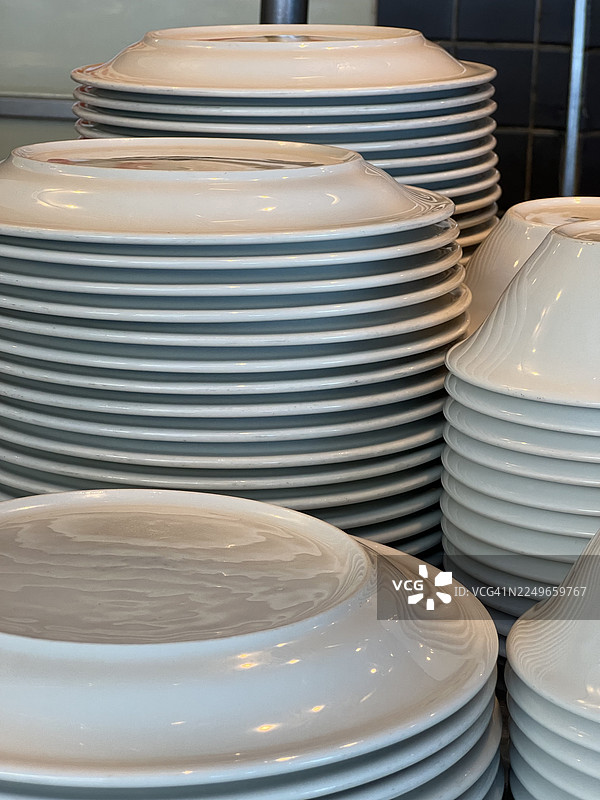 自助餐厅里叠放的白色陶瓷盘子和碗图片素材