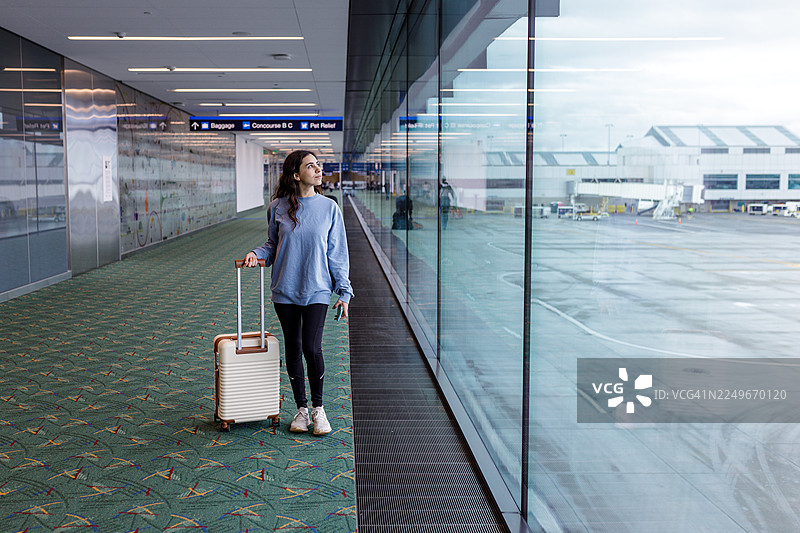 女子走向机场出发口，欣赏沿途风景图片素材