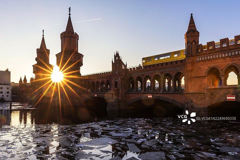日落时分，柏林德国首都，施普雷河上的浮冰与驶过的地铁列车，背景为上鲍姆桥图片素材