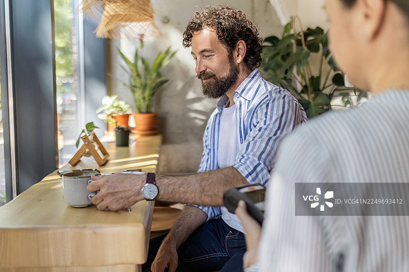 微笑的男人在咖啡馆用餐时用信用卡支付账单图片素材