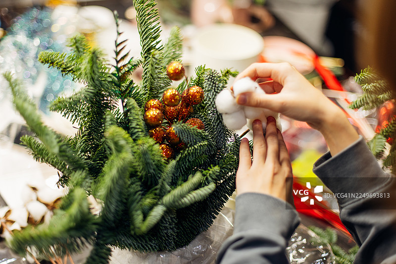 用装饰品装饰圣诞绿植摆设，用于圣诞餐桌装饰。圣诞树枝圣诞摆设制作大师班。图片素材