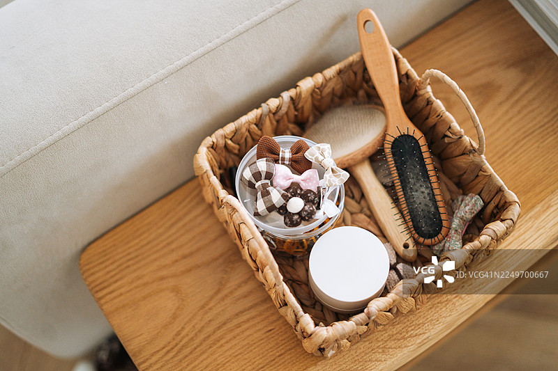 宠物美容用品，适用于小型犬：粉色蝴蝶结和梳子放在编织篮中，俯视平铺，可爱的宠物护理概念图片素材