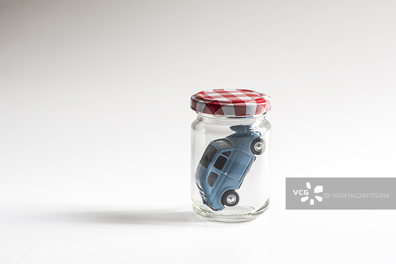 蓝色的玩具车被困在带有红色格子盖的玻璃罐里图片素材
