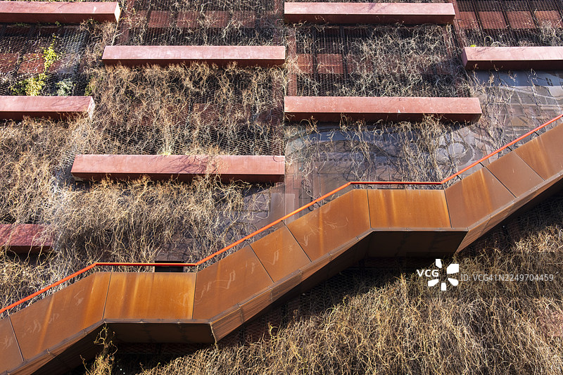 低角度仰视，可以看到带植被的立面、结合了停车场和 Nordhavn 社区回收站的建筑以及倾斜的楼梯图片素材