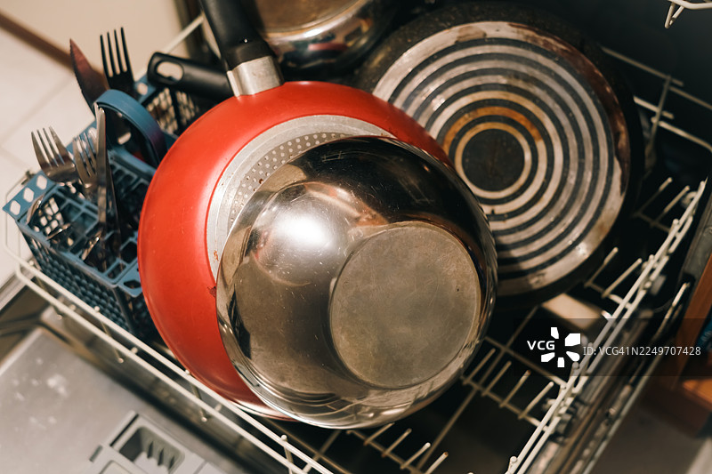 洗碗篮里堆放的脏餐具——盘子、锅具和餐刀图片素材