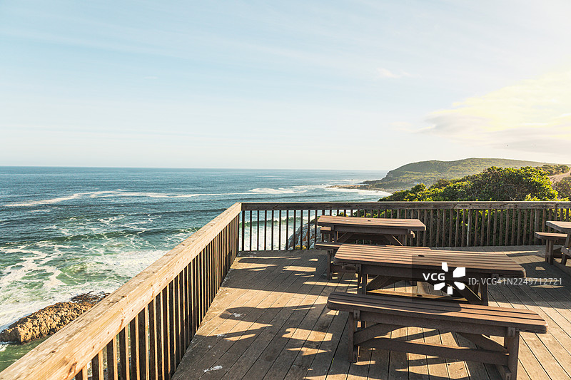 南非罗伯格自然保护区金色时段的风景海岸步道——岩石悬崖、木制小径和海洋景观图片素材