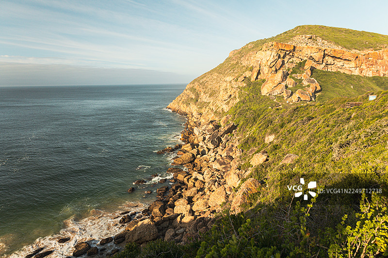 南非罗伯格自然保护区风景优美的海岸步道，在黄金时刻拍摄—岩石悬崖、木制步道和海景图片素材