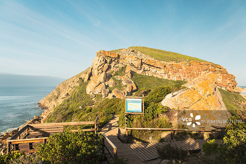 南非罗伯格自然保护区的风景优美的海岸步道，在黄金时刻拍摄——有岩石峭壁、木制栈道和海景图片素材