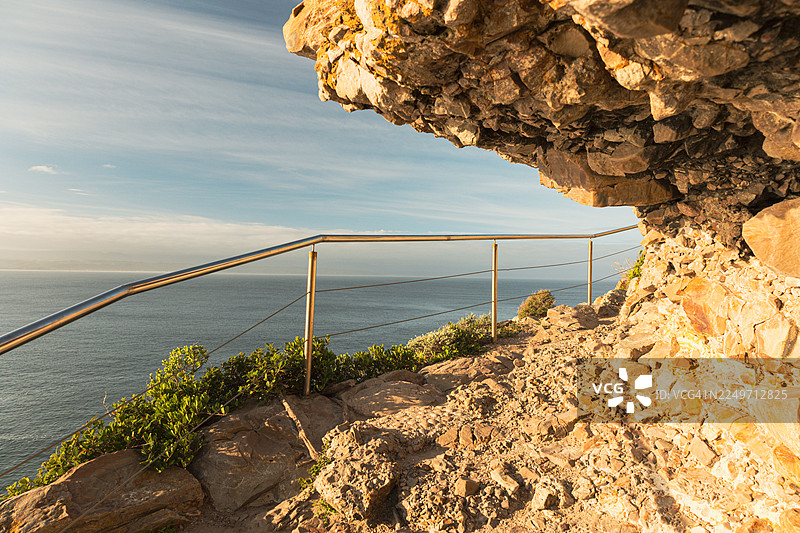 南非罗伯格自然保护区风景优美的海岸步道，金色时刻的岩石悬崖、木制栈道和海洋景色图片素材