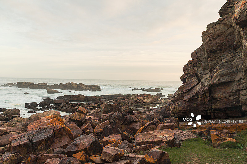 黄金时段的南非罗伯格自然保护区海滨风景步道——岩石悬崖、木栈道和海景图片素材