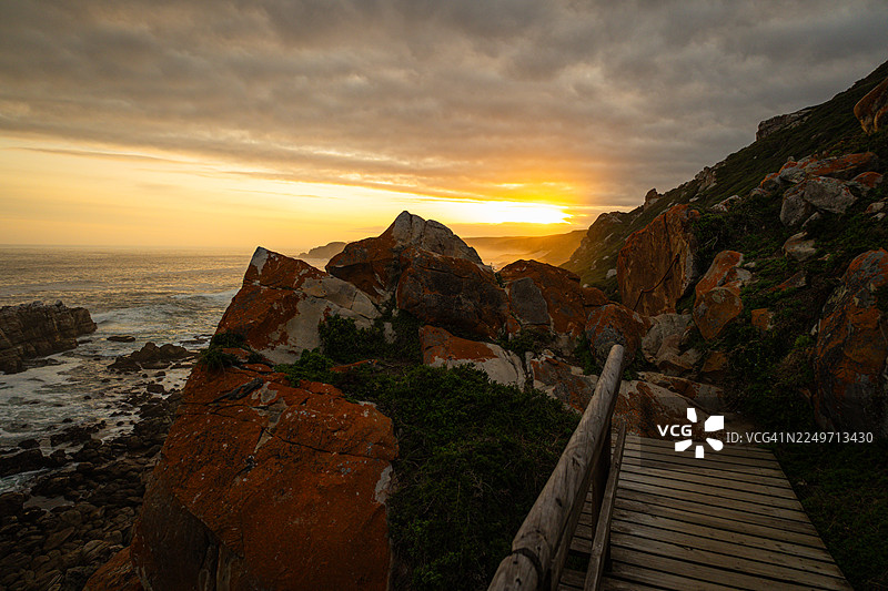 南非罗伯格自然保护区的海岸风景步道，在黄金时刻拍摄—岩石峭壁、木栈道和海景图片素材