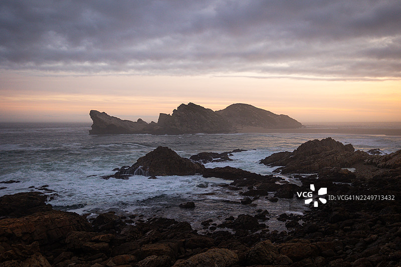 南非罗伯格自然保护区风景优美的海岸步道，在黄金时刻拍摄——岩石悬崖、木制栈道和海景图片素材