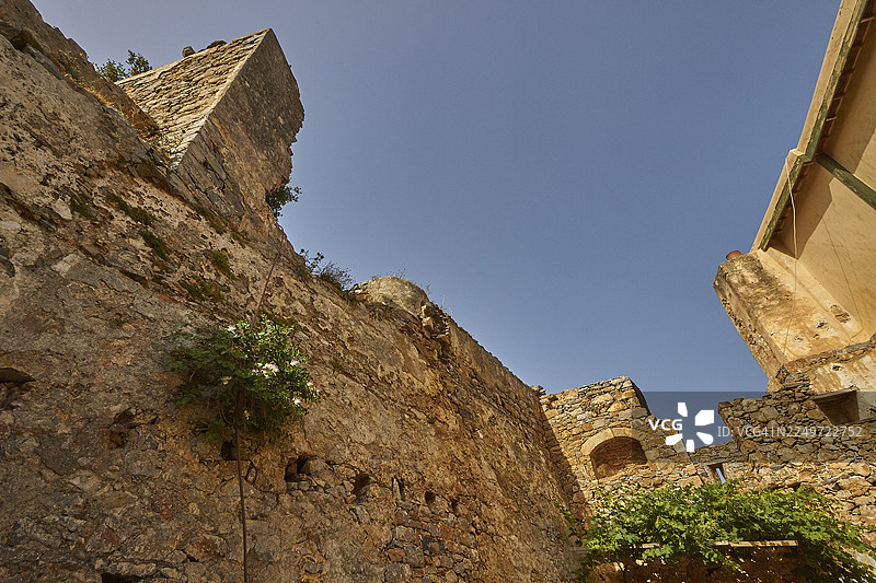 蓝天下的古老石墙，长满植被，有残垣断壁，位于希腊克里特岛东部米拉贝洛湾的埃卢达湾，斯皮纳隆加岛的威尼斯海堡。图片素材