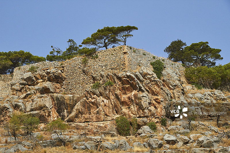 希腊克里特岛东部米拉贝洛湾的埃卢达湾，莱珀岛斯皮纳隆加的威尼斯海港古墙遗址，周围绿树环绕，天空晴朗图片素材