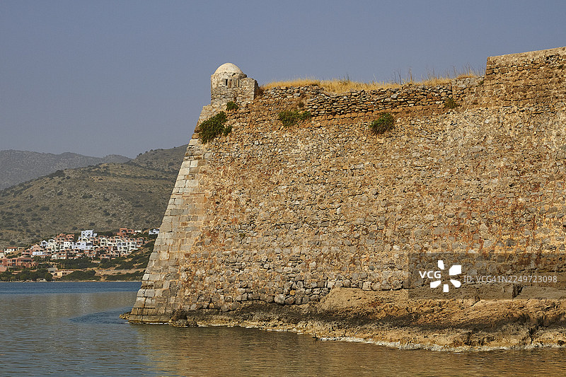 古老的石头墙矗立在海岸边，俯瞰着附近城镇和水域，包括威尼斯海堡、麻风岛、斯皮纳隆加、埃卢达湾、米拉贝罗湾、东克里特、克里特、希腊群岛、希腊。图片素材