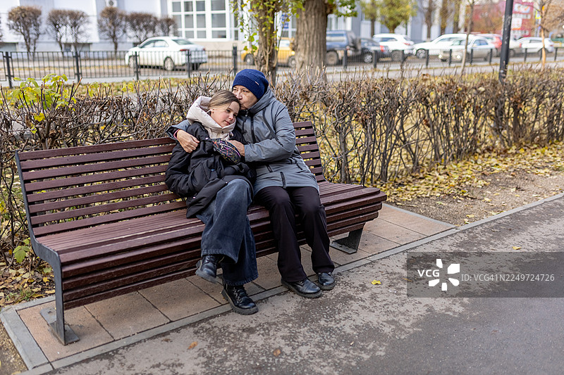 一位祖母和孙女在秋天的公园长椅上分享温馨的时刻图片素材