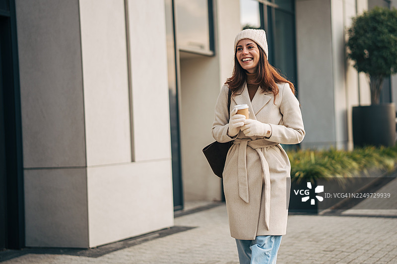 冬天，一位女士在城市里边走边喝咖啡图片素材