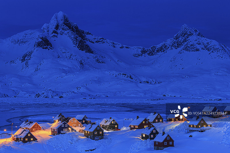 因纽特人定居点，房屋深埋在雪中，后面是山峦，蓝色时刻，黄昏，冬季，塔西拉克，东格陵兰，格陵兰图片素材