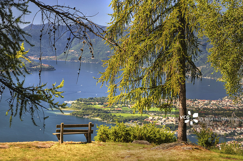 瑞士提契诺州洛迦诺和阿斯科纳，阳光明媚的夏日，阿尔卑斯山湖马焦雷湖的全景，湖边有长椅，远处有山峦图片素材