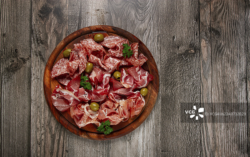 什锦切片肉类开胃菜，包括意大利熏火腿、萨拉米和火腿，搭配橄榄，放在木板上，早餐，俯视，特写，无人图片素材