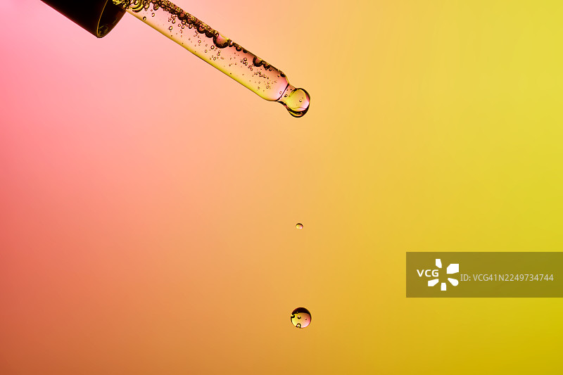 滴管将金黄色液体精华滴入空气中图片素材