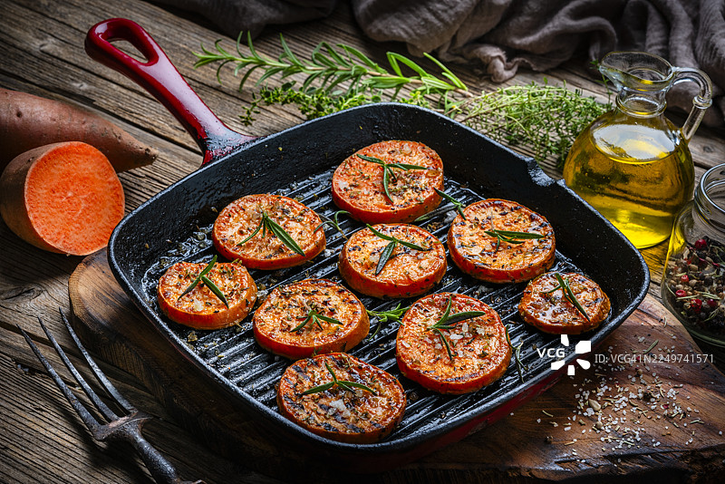 烤箱里的红薯片。迷迭香、食用油和胡椒。健康的烤根茎类蔬菜。烹饪或准备食物图片素材
