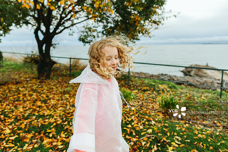 孩子在秋天树下快乐地旋转玩耍图片素材