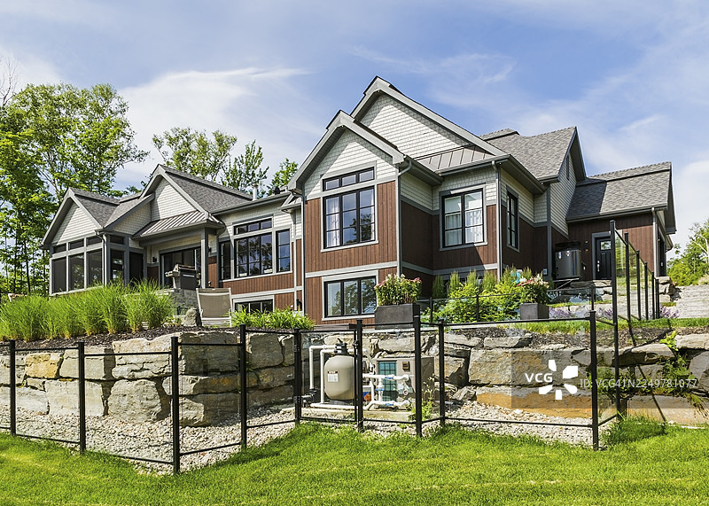 夏日加拿大魁北克，一座豪华平房风格的住宅，拥有天然石材、棕色染色木材和雪松瓦的后视图图片素材