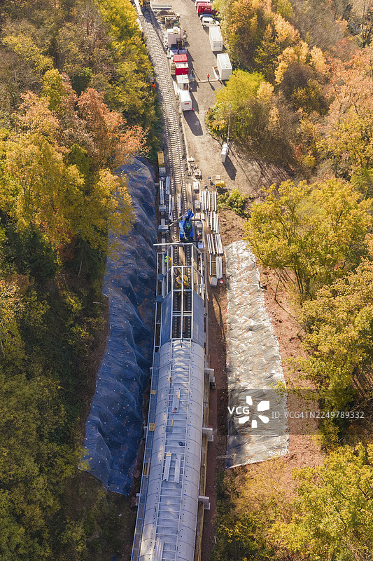 从鸟瞰视角看，秋日森林中的隧道施工现场正在进行材料运输，这里是德国黑森林卡尔夫的赫尔曼·黑塞铁路隧道施工现场。图片素材