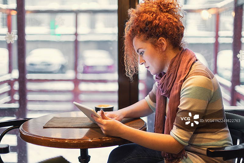 一位女士坐在咖啡馆里使用平板电脑图片素材
