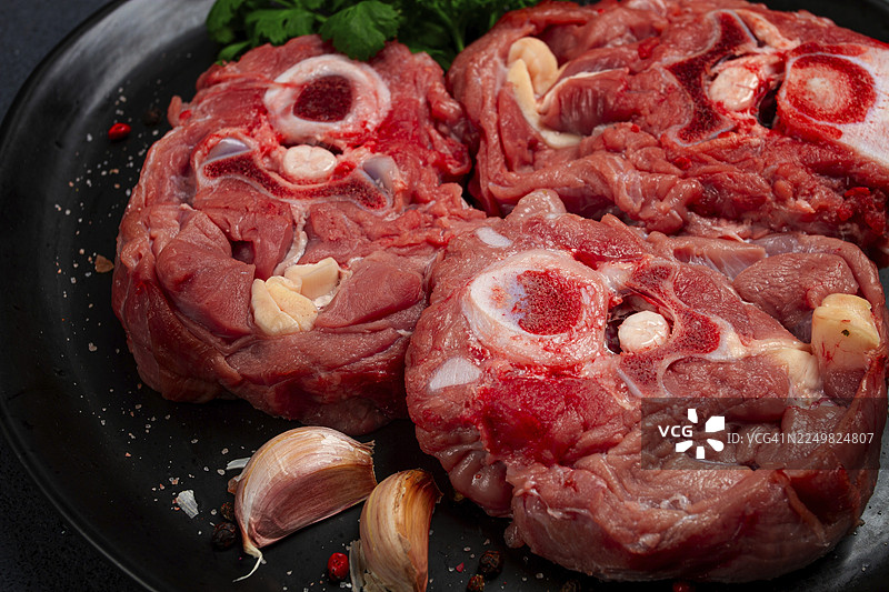 生的牛排，带骨小牛颈肉，新鲜肉类，放在黑色盘子上，俯视视角，无人图片素材