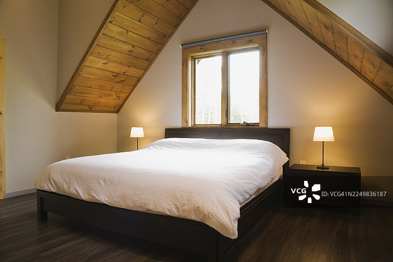 加拿大魁北克一间现代风格的木屋楼上的主卧室里，摆放着一张特大号床。图片素材