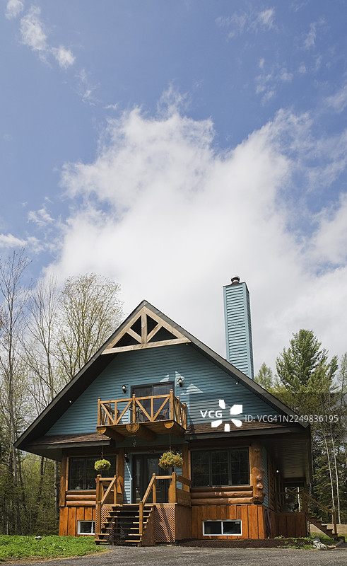 加拿大魁北克春季,一座带有蓝色护墙板装饰和木质元素的柱梁式小屋风格混合式原木房屋外观。此图片已获授权发布。CUPR0266图片素材